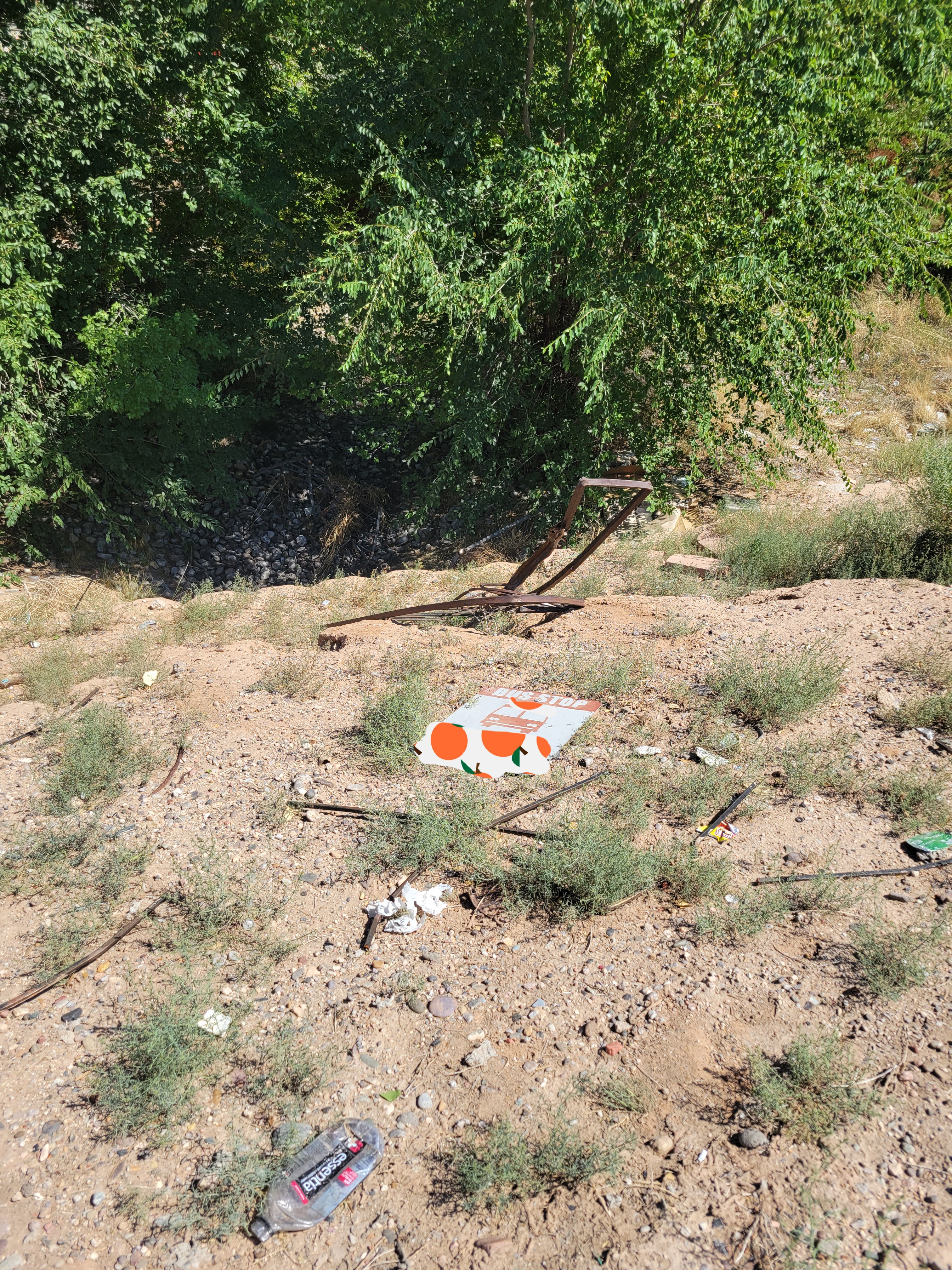 Bus stop sign and fence laying on ground.